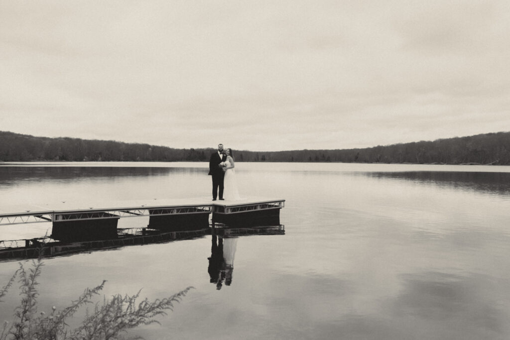 Eloping couple standing on the dock at Big Bass Lake in the Pocono Mountains, Pennsylvania